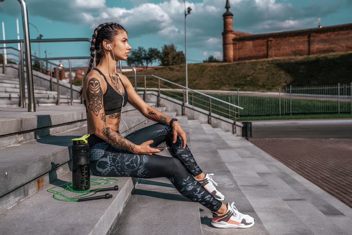 une femme sportive assise avec un shaker de whey protéine